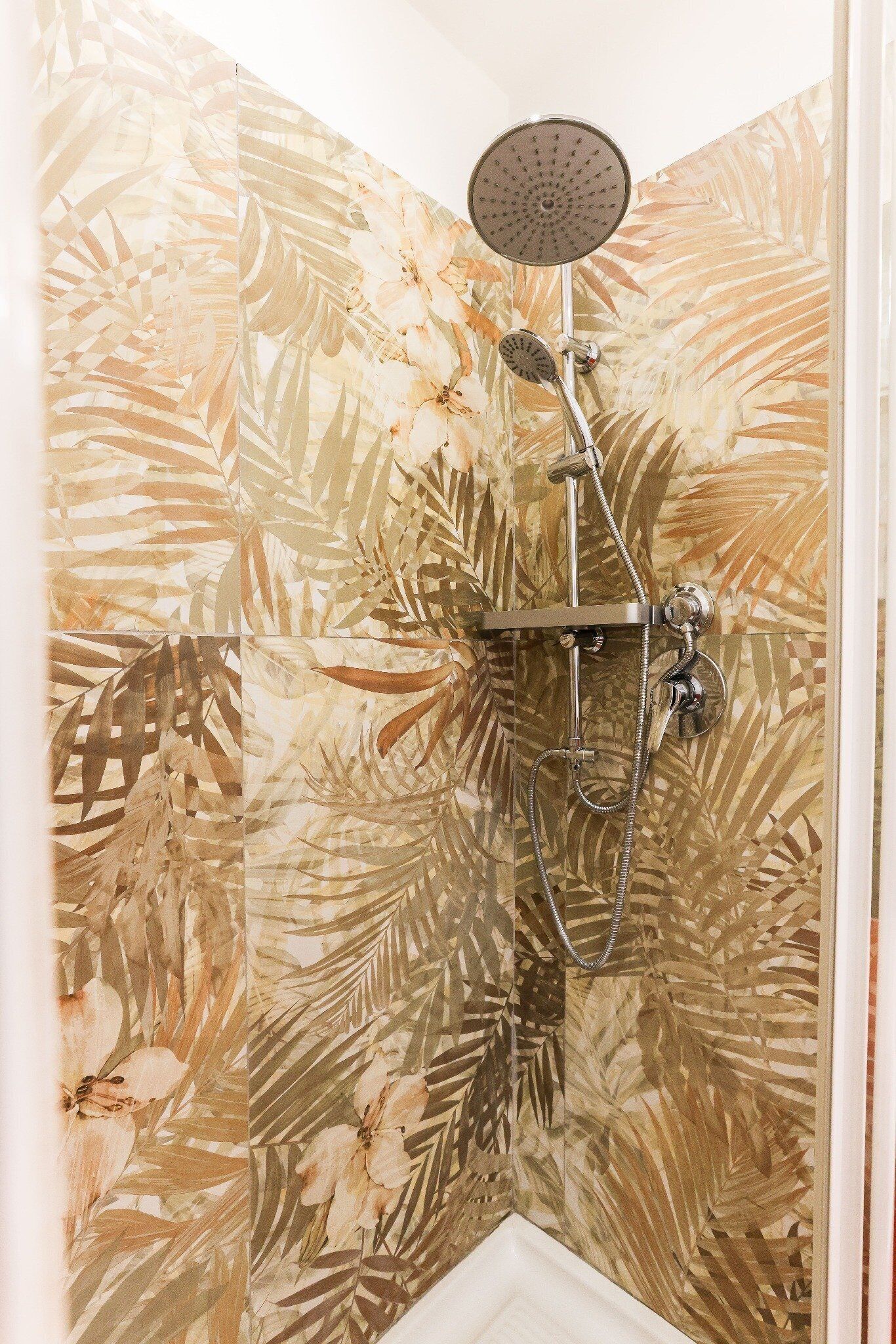 A shower with a handheld showerhead and a handheld rain shower attachment.