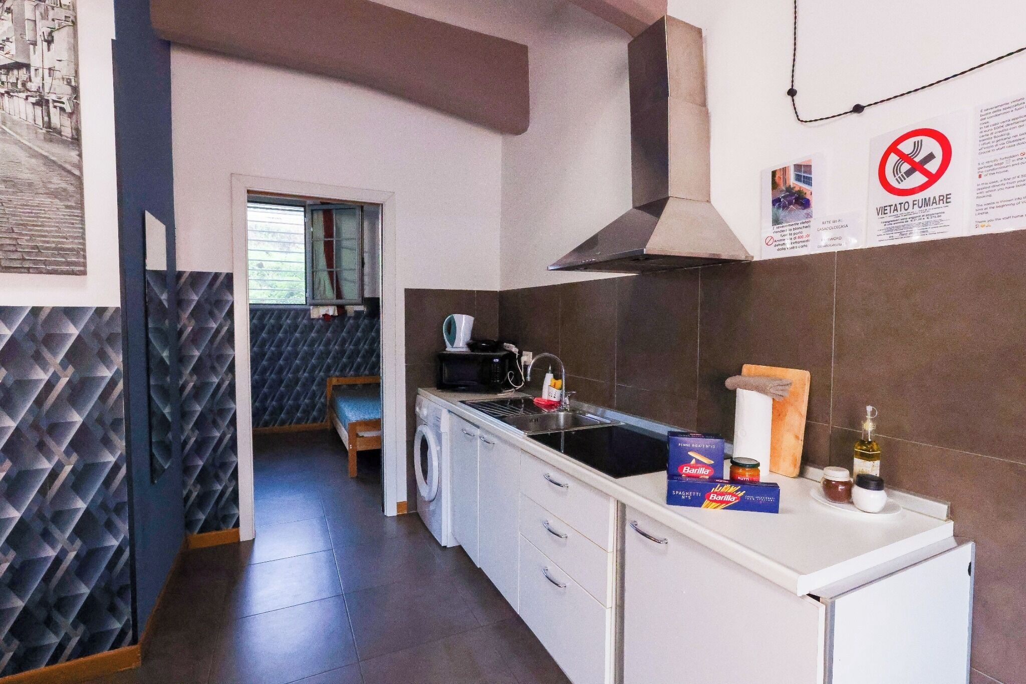A modern kitchen with a washing machine, a microwave, and a sink. There are barista coffee beans and a bottle of olive oil on the counter.