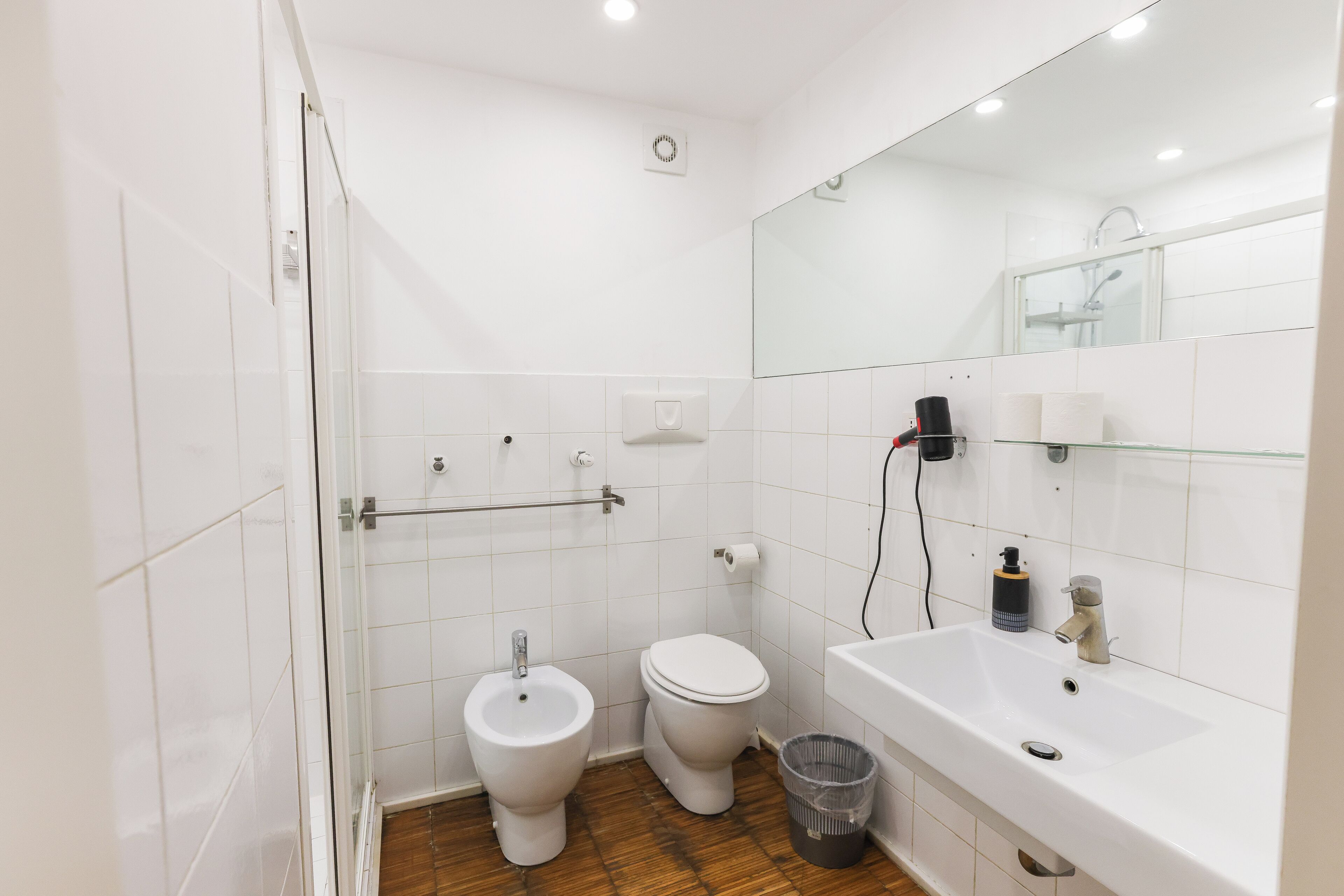 A modern bathroom with a glass shower enclosure, a white toilet, and a sink with a mirror above it.