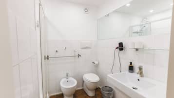 A modern bathroom with a glass shower enclosure, a white toilet, and a sink with a mirror above it.