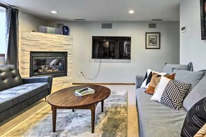 A modern living room with a fireplace, a sofa, a coffee table, and a TV mounted on the wall. - Lovely apartment in vibrant Seattle (Seattle)
