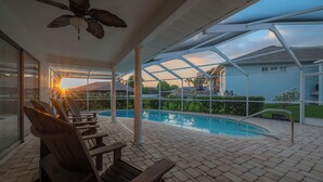 A covered outdoor area with a pool, wooden lounge chairs, and a ceiling fan. - Waterfront 3BR/2BR Coastal Retreat w/ Pool (Apollo Beach)
