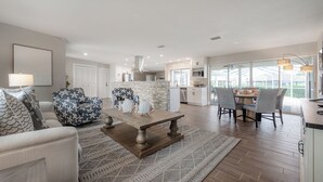 A modern living room with a wooden coffee table, a sofa, and patterned armchairs. - Waterfront 3BR/2BR Coastal Retreat w/ Pool (Apollo Beach)