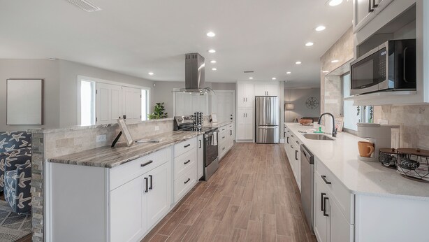A modern kitchen with white cabinetry, a stainless steel range hood, and a built-in microwave. - Waterfront 3BR/2BR Coastal Retreat w/ Pool (Apollo Beach)