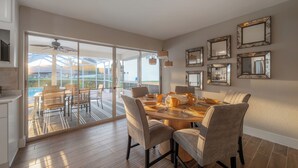 A dining area with a large table, chairs, and a view through glass doors to an outdoor deck. - Waterfront 3BR/2BR Coastal Retreat w/ Pool (Apollo Beach)
