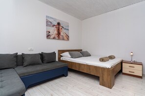 Une chambre à coucher moderne avec un lit en bois, un canapé gris et une table de chevet avec une lampe.