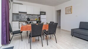 Une cuisine moderne avec des meubles blancs, un pare-feu décoré et un coin repas avec une table dressée pour quatre personnes.