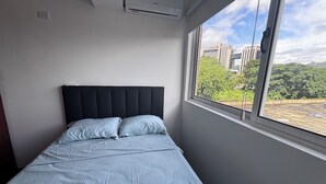 A bedroom with a bed, a window, and an air conditioning unit.