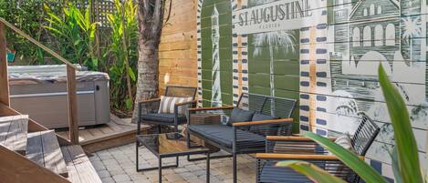 An outdoor patio with a wooden deck, a hot tub, and outdoor furniture.