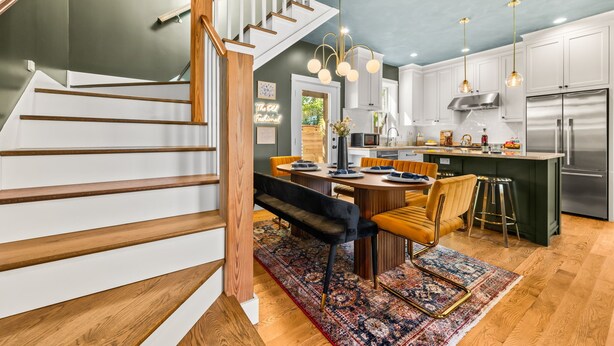 A modern kitchen with a central island, stainless steel appliances, and a dining area with a bench and chairs. - Designer Spa Retreat Near Historic Downtown! Pets! Luxury Walk to Shops & Dining (St. Augustine)