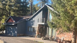 Eine rustikale Holzhütte mit Stein Fundament, einer Holzterrasse und einer Garage.