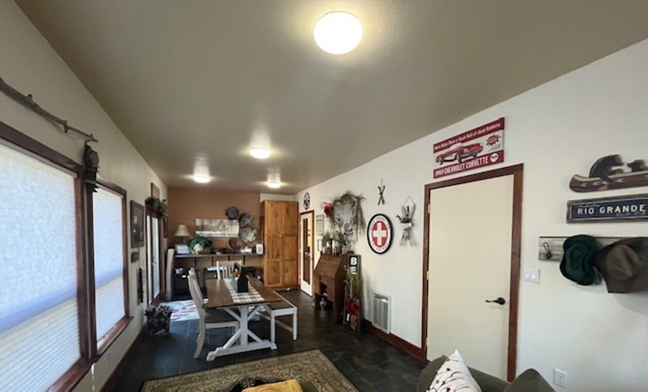 A spacious living room with a dining area, a kitchen in the background, and a door with a sign.