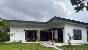 A modern house with a covered patio, a lawn, and a pathway leading to the entrance. - Villa Luciérnaga: Private Pool and Total Relaxation (Provincia de Alajuela)