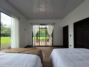 Une chambre d’hôtel avec deux lits, une vue sur le jardin et un patio aménagé avec des chaises.