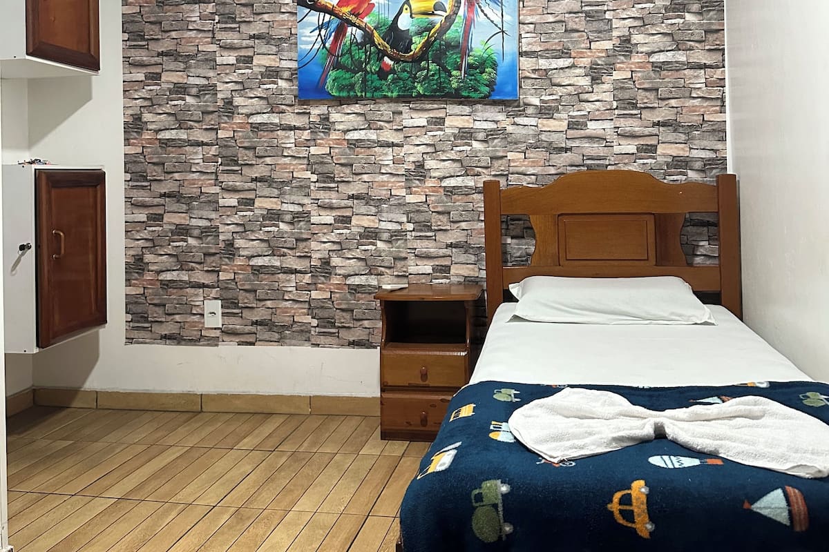 Un dormitorio con cama, mesita de noche, armario y pared con diseño de piedra.