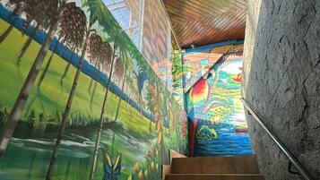 A staircase with a mural on the wall, leading to a room with a wooden ceiling.