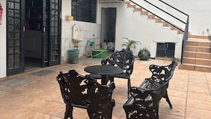 A patio with a table and chairs, a staircase, and a door leading to a room.