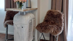 A room with a vintage-style radiator, a small table with a vase of flowers, and two furry chairs. A poster on the wall reads "Life is full of questions, Cupcakes are the answer." - Lakeside Heaven. Apartment directly in the Lipno reservoir (Frymburk)