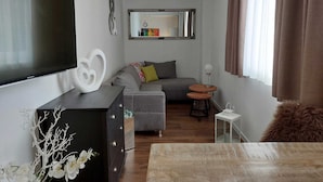 A modern living room with a flat-screen TV, a sofa, a coffee table, and a dining table. - Lakeside Heaven. Apartment directly in the Lipno reservoir (Frymburk)