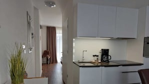 A modern kitchen with white cabinets, a black countertop, and a coffee maker. - Lakeside Heaven. Apartment directly in the Lipno reservoir (Frymburk)