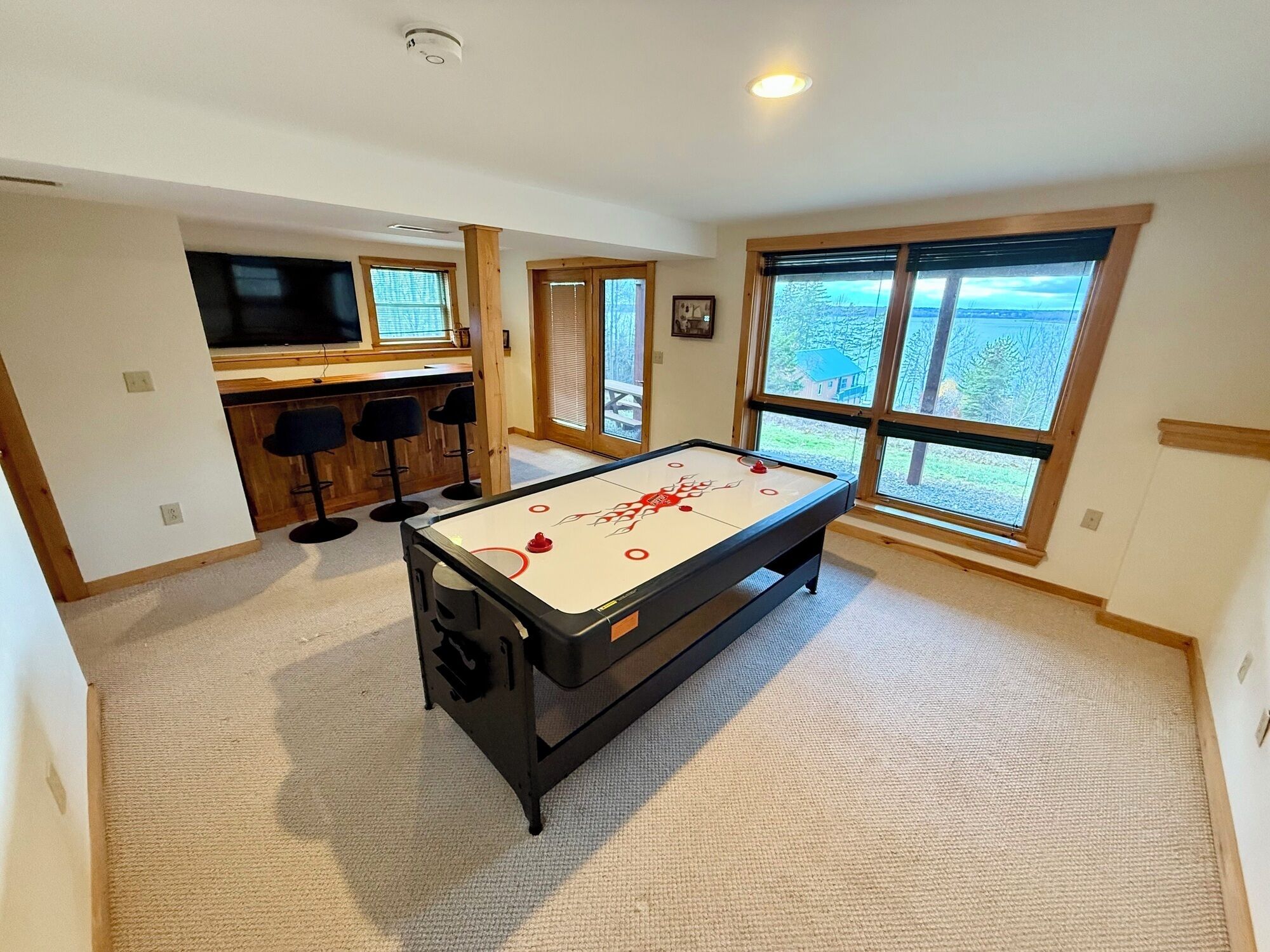 Une pièce spacieuse équipée d’une table de billard, d’un coin bar et de grandes fenêtres offrant une vue dégagée.