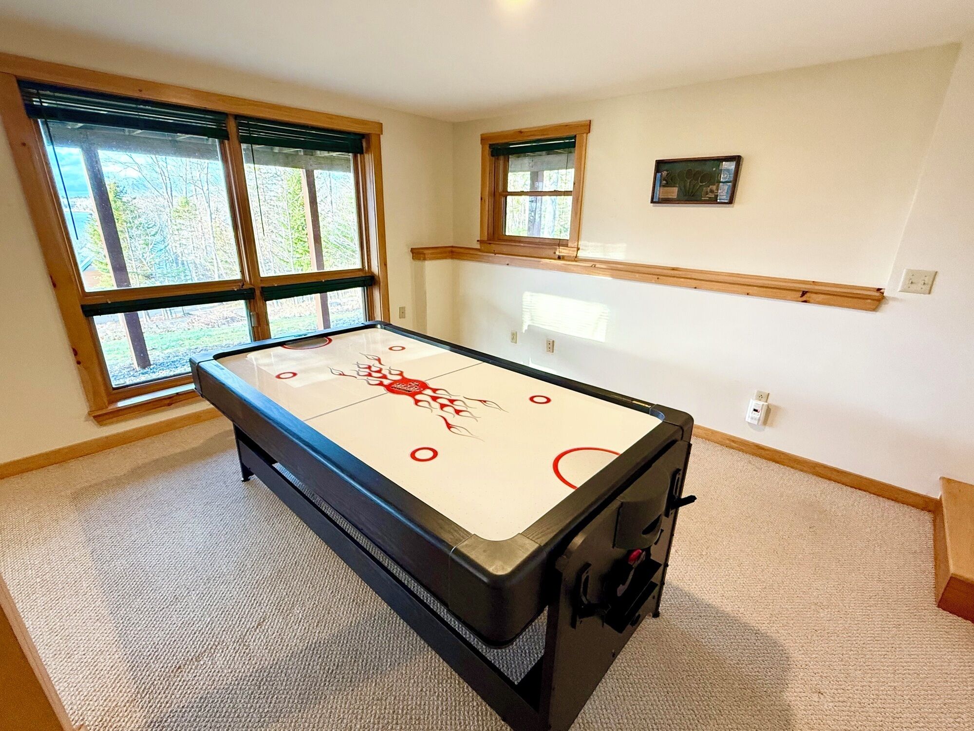 A room with a shuffleboard table, large windows, and a wooden ceiling.