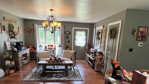 Ein gemütliches Wohnzimmer mit Couchtisch, Sesseln, einer Chandelier und einem Bücherregal.
