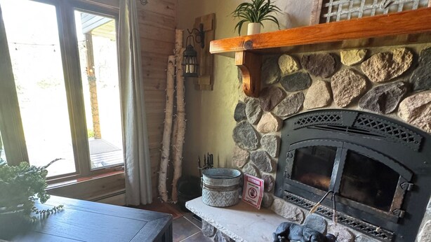 Ein gemütliches Interieur mit Kamin aus Stein, Holzbalken und einer rustikalen Steinwand.