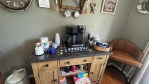 A kitchenette with a coffee maker, cups, and a Scrabble game.