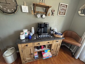 Une petite cuisine équipée d’une machine à café, de tasses et d’un jeu de Scrabble.