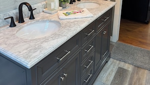 A modern bathroom with a double sink, dark cabinetry, and a mirror with a wooden frame.