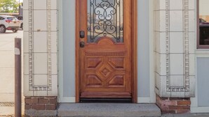 Una puerta de madera con detalles metálicos elaborados, en un edificio con paredes de azulejos decorativos.