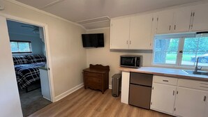 Una cocina compacta con armarios blancos, microondas y lavavajillas.