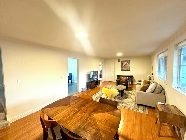 Un salón amplio con una mesa de comedor de madera, un sofá y un televisor.