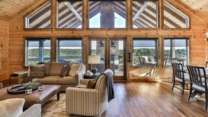 A spacious loft-style room with a high ceiling, large windows, and a fireplace. - Toccoa Vista Pool & Spa |Mineral Bluff, GA (Mineral Bluff)