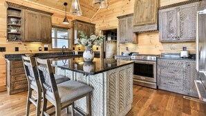 A kitchen with wooden cabinets, a central island, bar stools, and stainless steel appliances. - Toccoa Vista Pool & Spa |Mineral Bluff, GA (Mineral Bluff)