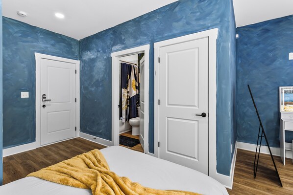 Un dormitorio con cama, una manta amarilla, una puerta blanca y una pared azul.
