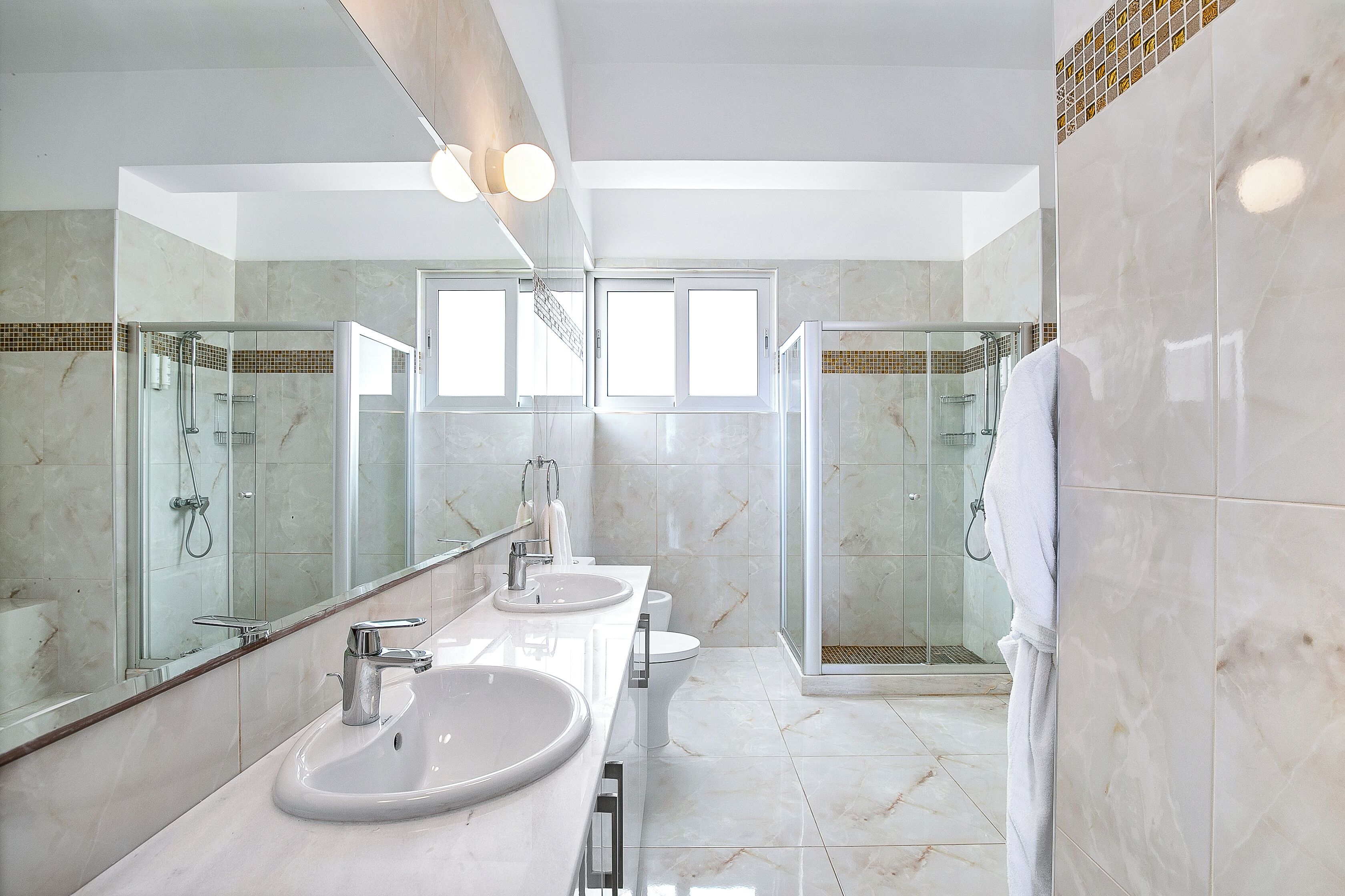 A modern bathroom with two sinks, a glass shower enclosure, and a large mirror.