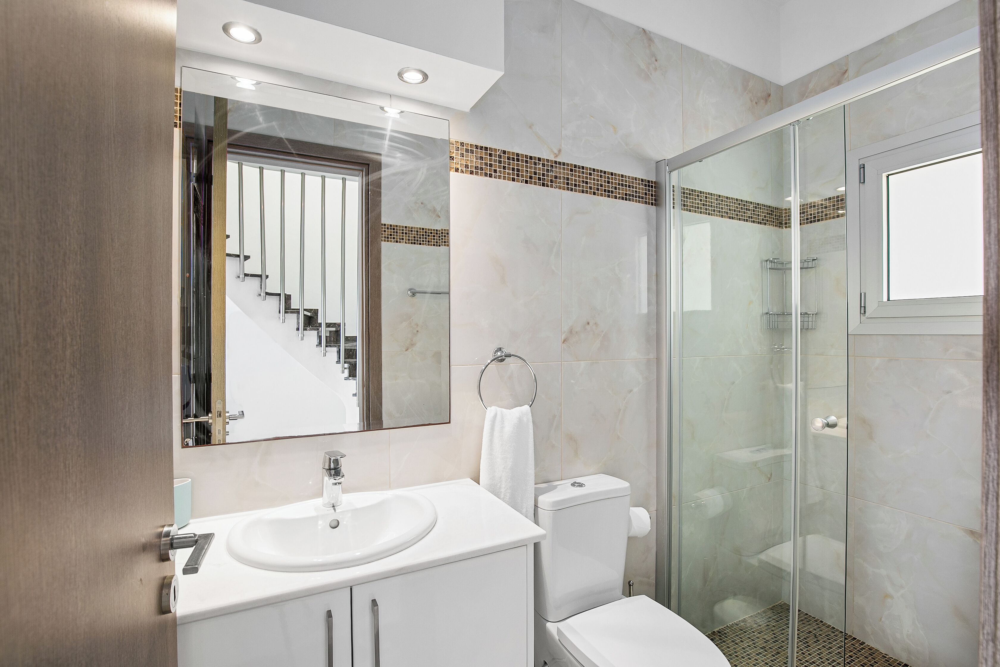 A modern bathroom with a glass-enclosed shower, a white sink, and a toilet.