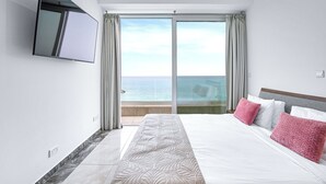 A hotel room with a large bed, a TV mounted on the wall, and a balcony with a view of the sea. - Olymp Luxury Villa D (Kissonerga)