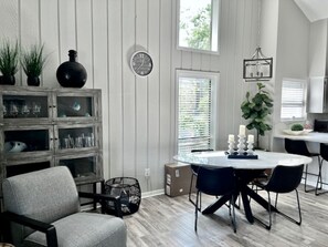 A dining area with a round table, black chairs, and a cabinet with glass doors.