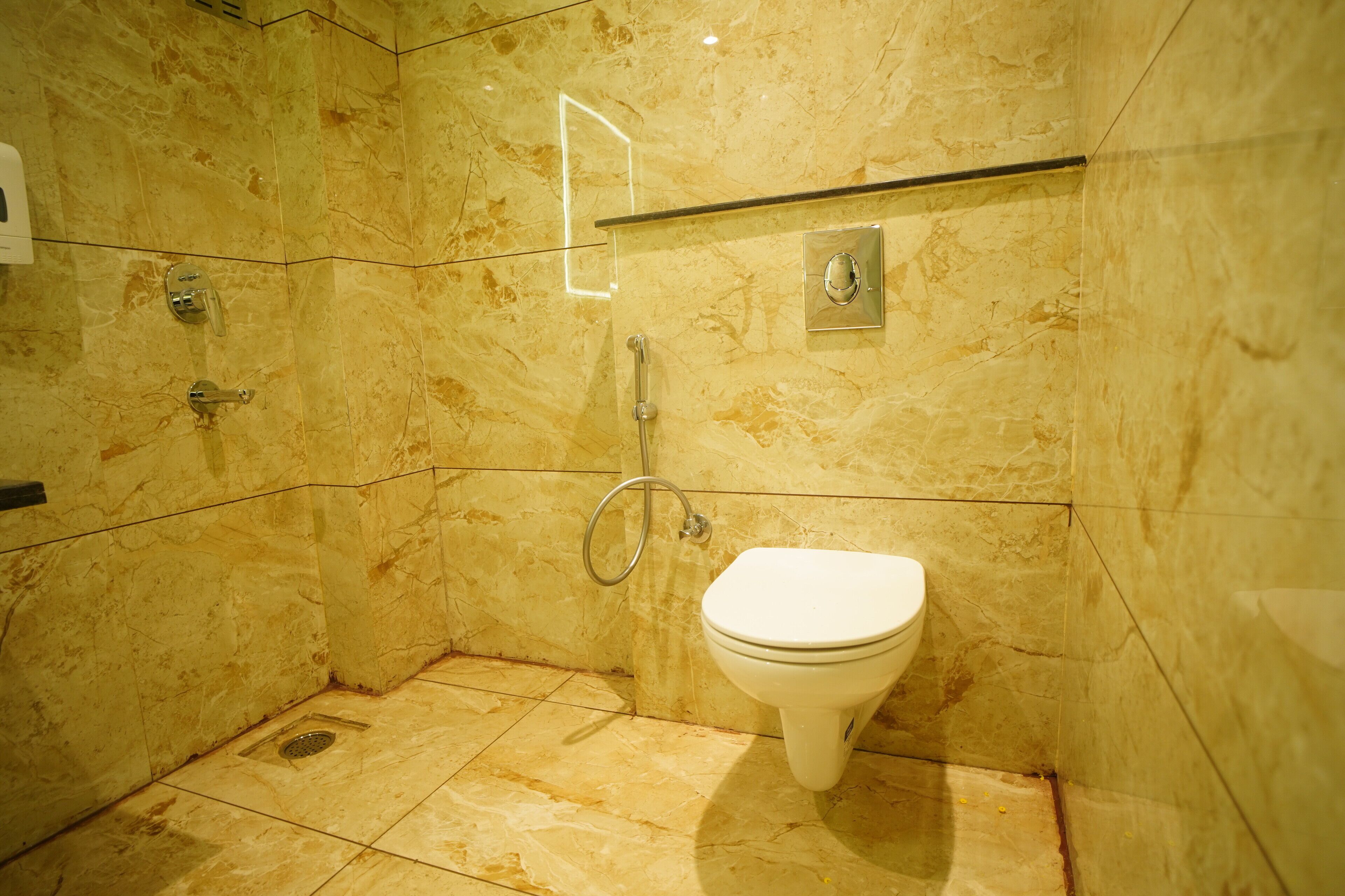 A modern bathroom with a marble floor, a glass shower enclosure, and a white toilet.