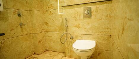 A modern bathroom with a marble floor, a glass shower enclosure, and a white toilet.