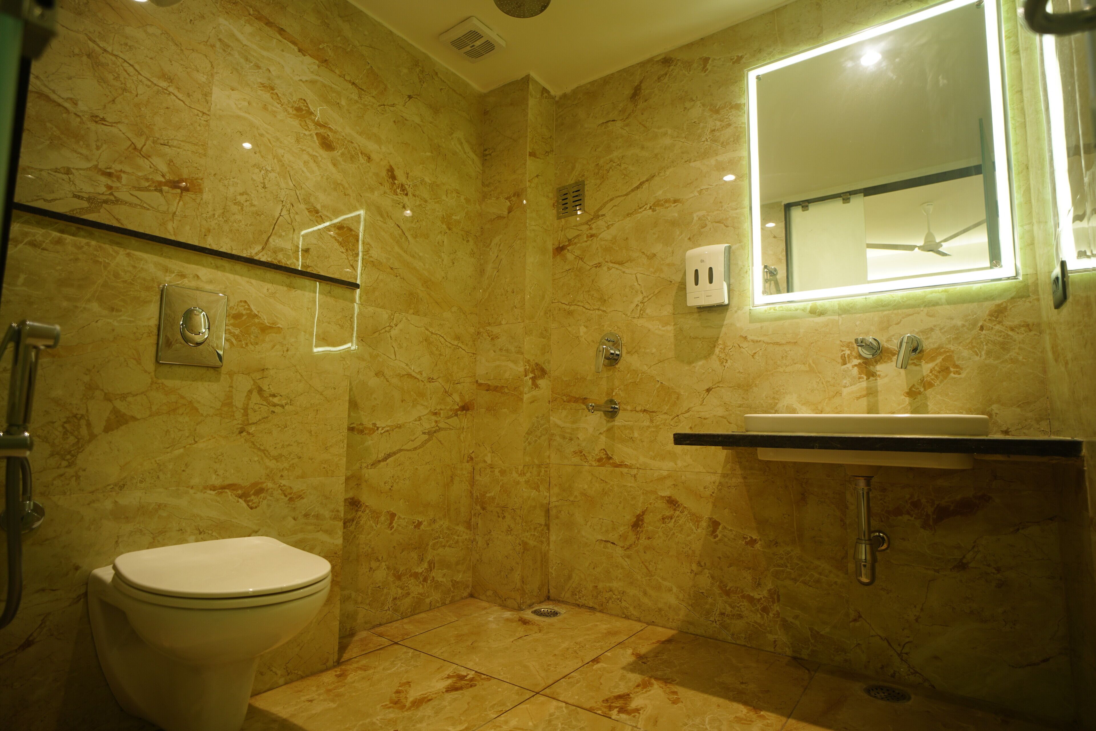 A bathroom with a marble floor, a toilet, a sink, and a mirror.
