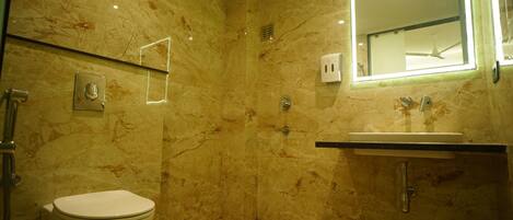 A bathroom with a marble floor, a toilet, a sink, and a mirror.