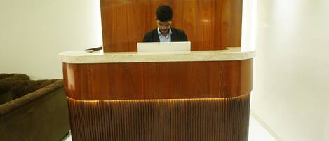 A reception desk with a wooden finish and a person seated behind it.