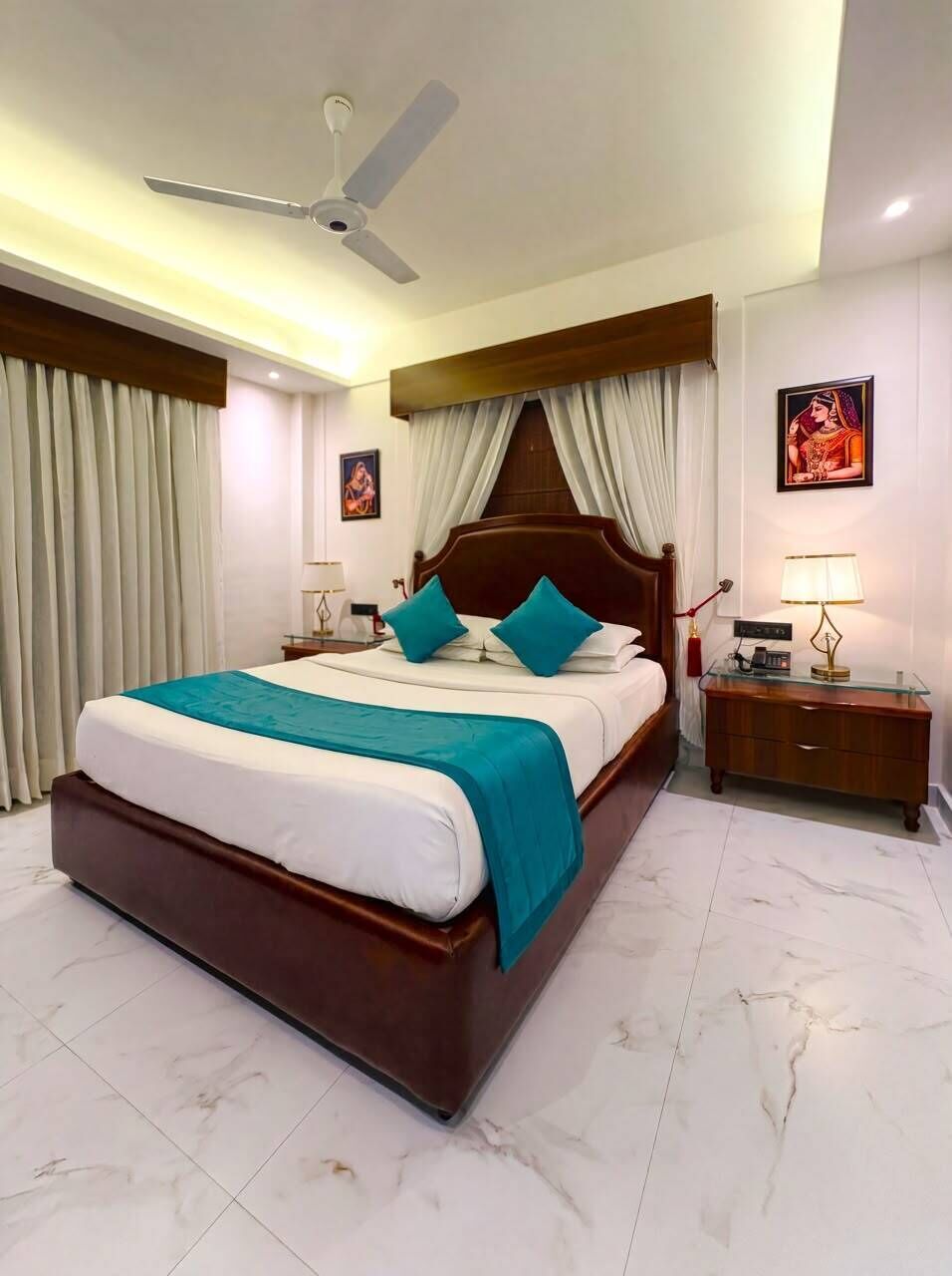 A hotel room with a large bed, a ceiling fan, a nightstand with a lamp, and a picture on the wall.