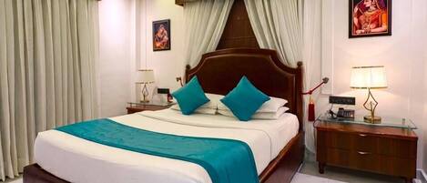 A hotel room with a large bed, a ceiling fan, a nightstand with a lamp, and a picture on the wall.