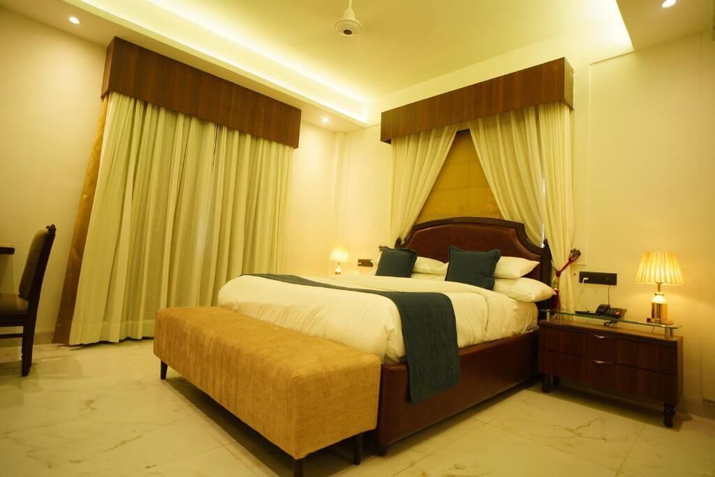 A bedroom with a large bed, a bedside table with a lamp, and a bench.