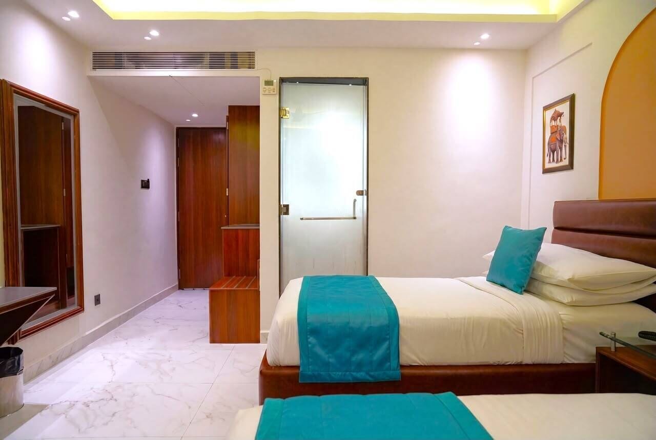 A hotel room with a bed, bedside table, and a door leading to another room.